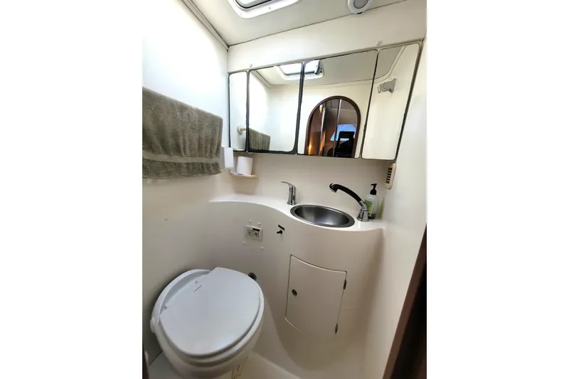 Slide: The Image of Compact bathroom in a 1995 Lagoon TPI boat with toilet, sink, and mirror. - 18