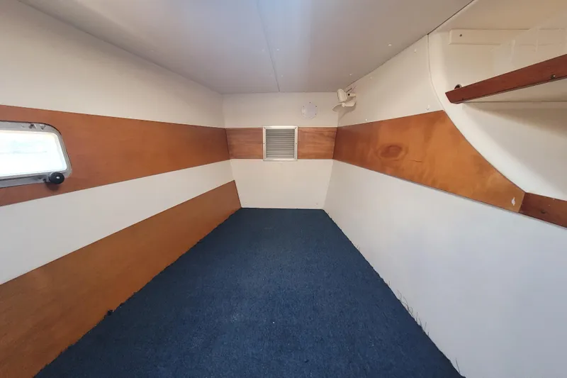 Slide: The Image of Interior of a 1995 Lagoon TPI boat cabin with wood paneling and blue carpet. - 19
