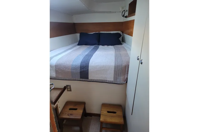 Slide: The Image of Cozy cabin bedroom in 1995 Lagoon TPI boat with striped bedding and wooden stools. - 22
