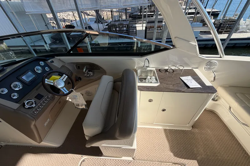 Slide: The Image of 2013 Sea Ray 300 SLX boat interior with helm, sink, and seating area. - 15