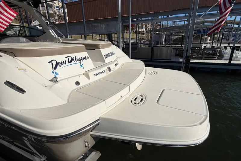 Slide: The Image of 2013 Sea Ray 300 SLX boat docked, featuring "Dew Diligence" name and swim platform. - 7
