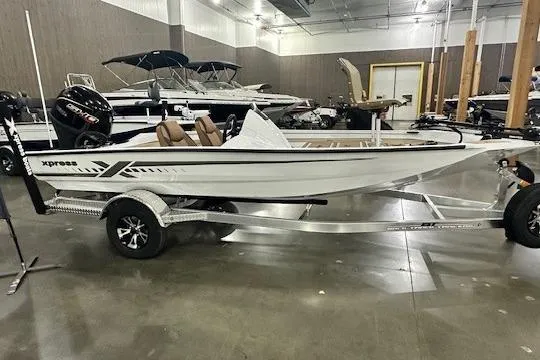 The Image of 2026 Xpress H18C Crappie boat on trailer in showroom, featuring sleek design and modern features. - 0