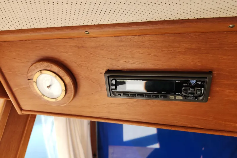 Slide: The Image of 1983 Grand Banks 36 Classic interior with wooden paneling, featuring a stereo system and gauge. - 19