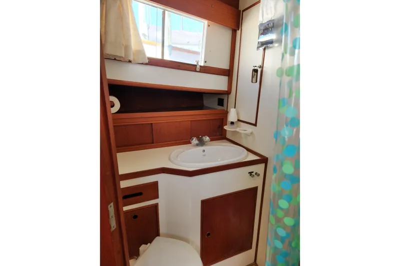 Slide: The Image of 1983 Grand Banks 36 Classic yacht bathroom with sink, wooden cabinetry, and porthole window. - 25