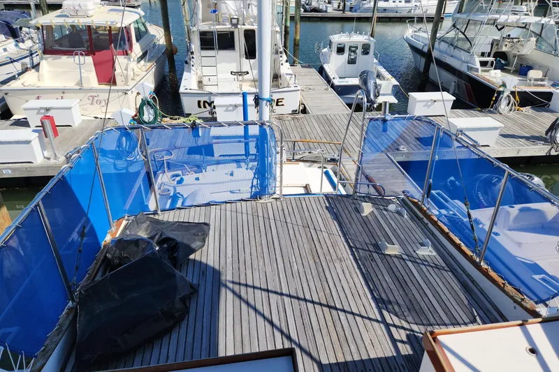 Slide: The Image of 1983 Grand Banks 36 Classic yacht docked at marina, featuring spacious deck and blue railings. - 36