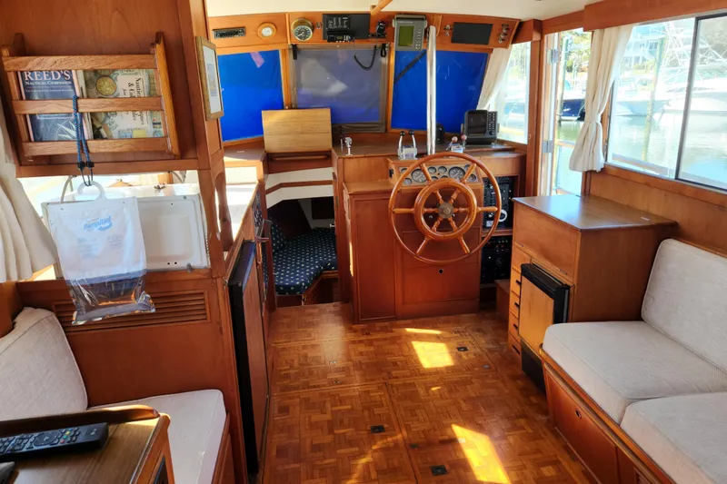Slide: The Image of 1983 Grand Banks 36 Classic yacht interior with wooden helm, seating, and nautical decor. - 4