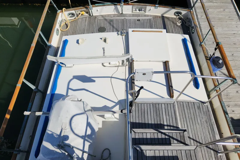 Slide: The Image of 1983 Grand Banks 36 Classic boat deck with wooden and metal railings, docked at marina. - 42