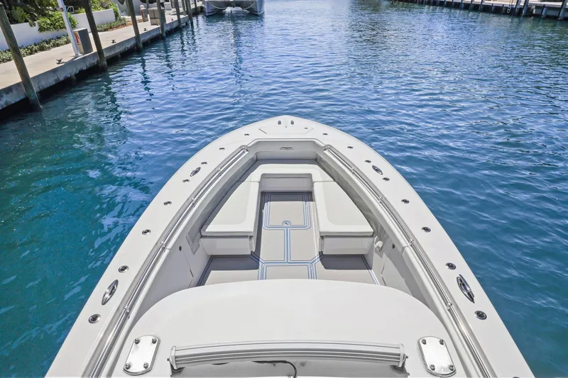 Slide: The Image of 2013 Invincible 42 Open Fisherman boat interior with cushioned seating under a blue sky. - 37