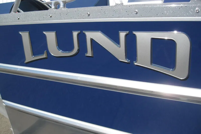 Slide: The Image of 2026 Lund 185 Heavy Gauge boat displayed outside a marine dealership. - 3