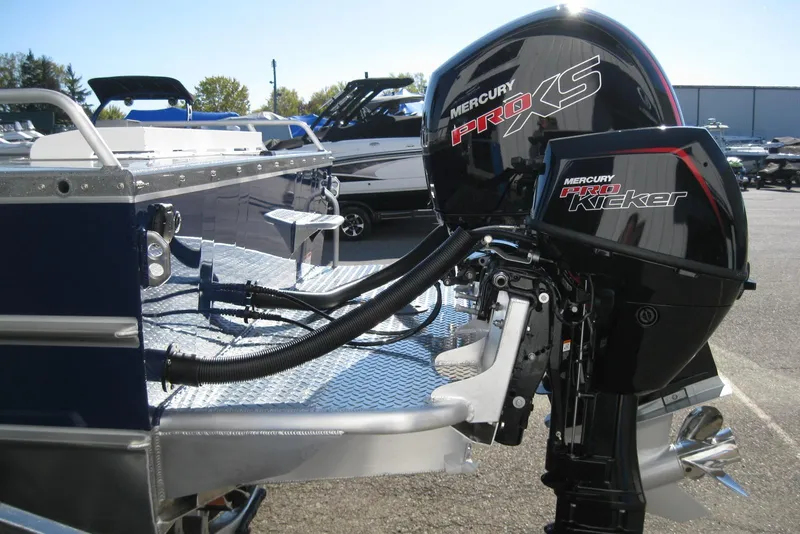 Slide: The Image of 2026 Lund 185 Heavy Gauge boat with dual Mercury outboard motors, parked outdoors. - 7