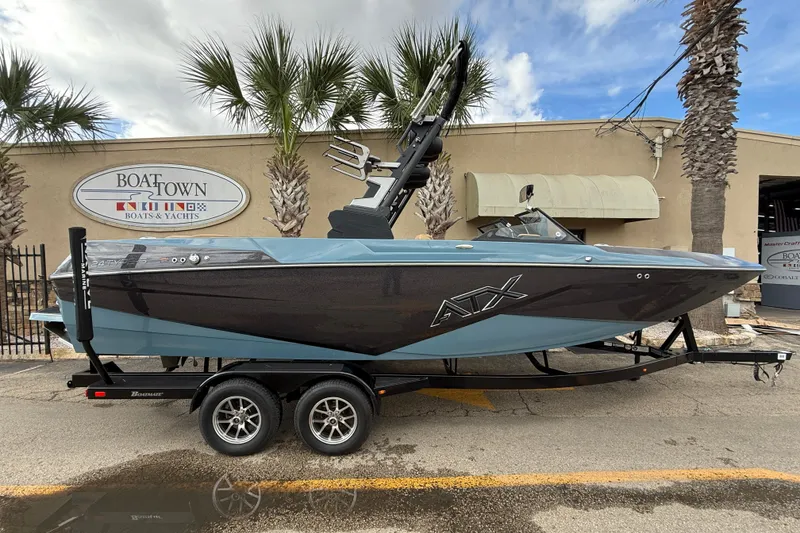 The Image of 2023 ATX boat on trailer at Boat Town dealership, palm trees in background. - 0