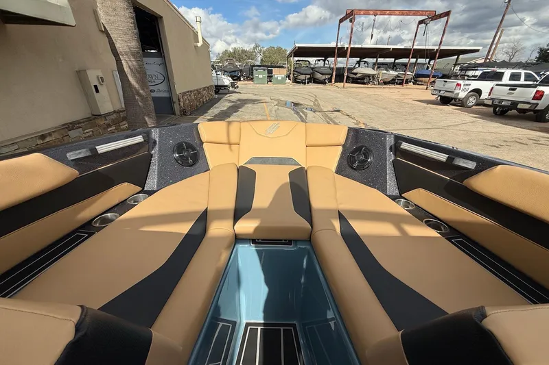 Slide: The Image of 2023 ATX boat interior with tan and black seating, parked outdoors. - 12