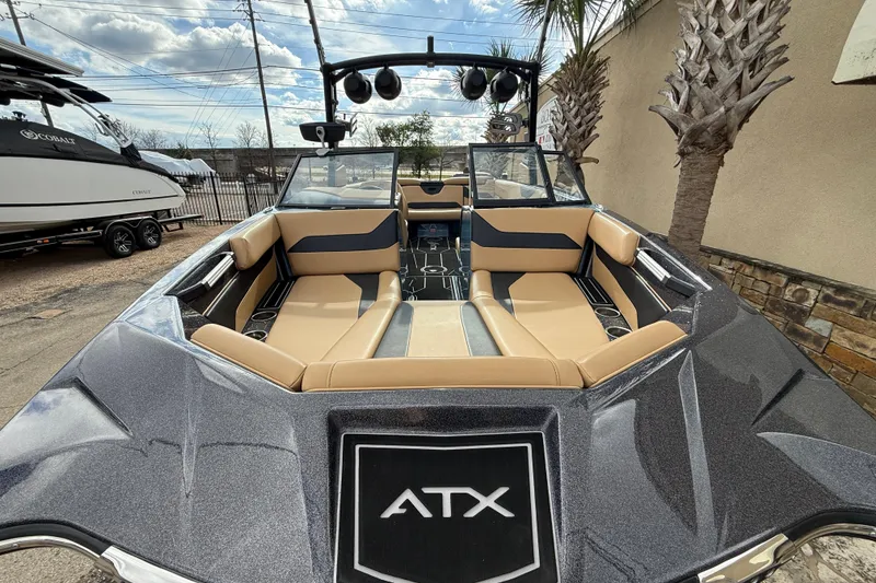 Slide: The Image of 2023 ATX boat interior with tan and black seating, outdoor setting. - 2