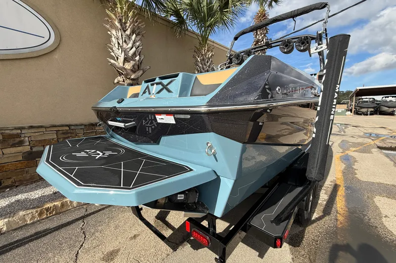 Slide: The Image of 2023 ATX boat model with sleek design, parked outdoors under palm trees. - 4