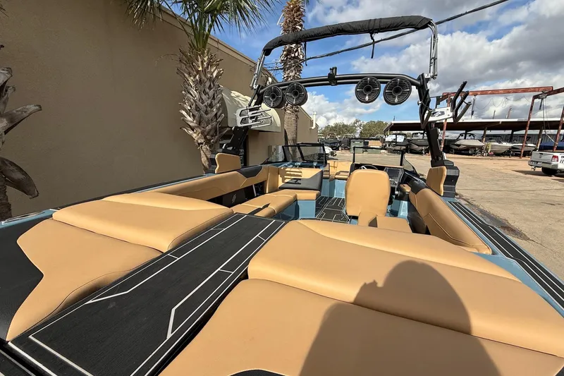 Slide: The Image of 2023 ATX boat interior with tan seats and black accents, parked outdoors. - 8