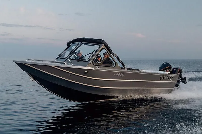 Slide: The Image of Manufacturer Provided Image: 2025 Lund 200 Heavy Gauge boat on calm water, surrounded by lush greenery. - 24