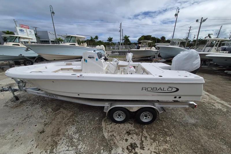 The Image of 2026 Robalo 226 Cayman boat on trailer, displayed outdoors at a dealership. - 1