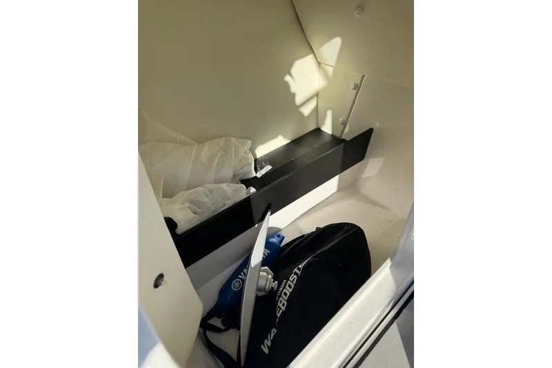 Slide: The Image of 2020 Yamaha Boats 242X E-Series storage compartment with wakeboard gear and accessories. - 20