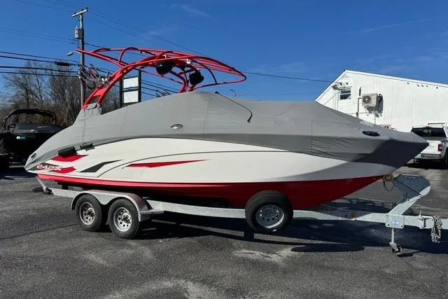 Slide: The Image of 2020 Yamaha Boats 242X E-Series on trailer, covered, with red accents, parked outdoors. - 5