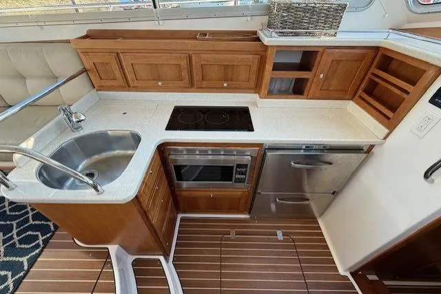 Slide: The Image of 2015 Back Cove 37 yacht kitchen with wooden cabinets, sink, stove, and microwave. - 14