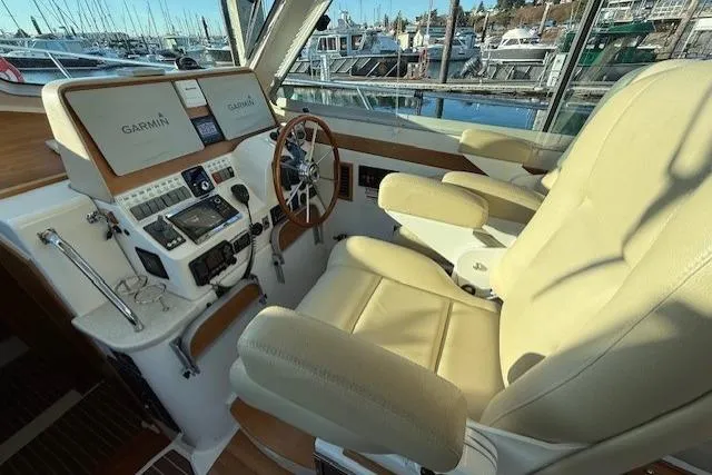 Slide: The Image of 2015 Back Cove 37 helm with Garmin navigation, leather seats, and marina view. - 15