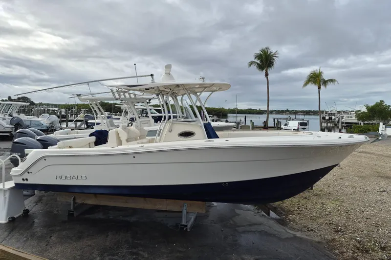 The Image of 2014 Robalo R300 Center Console boat docked near palm trees and marina. - 1
