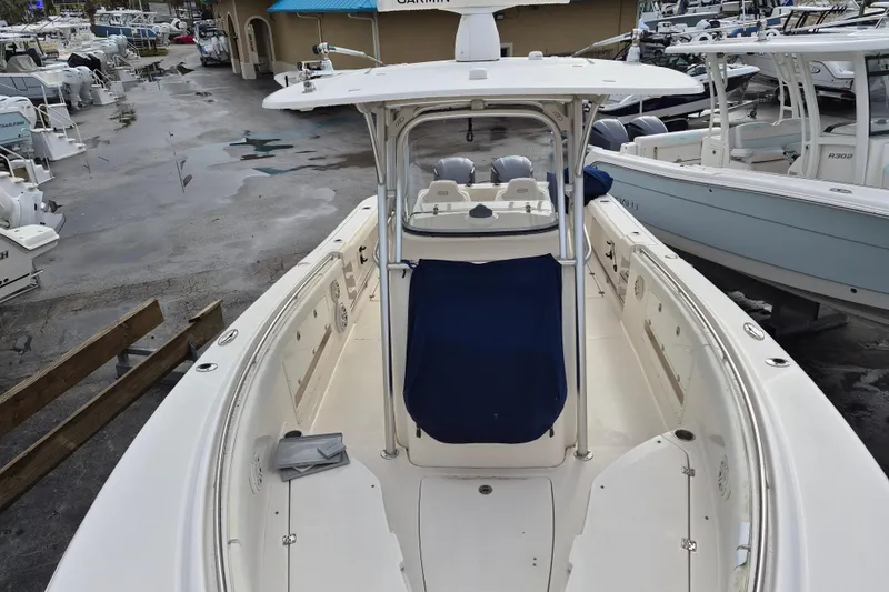 Slide: The Image of 2014 Robalo R300 Center Console boat in marina, showcasing spacious deck and helm. - 12