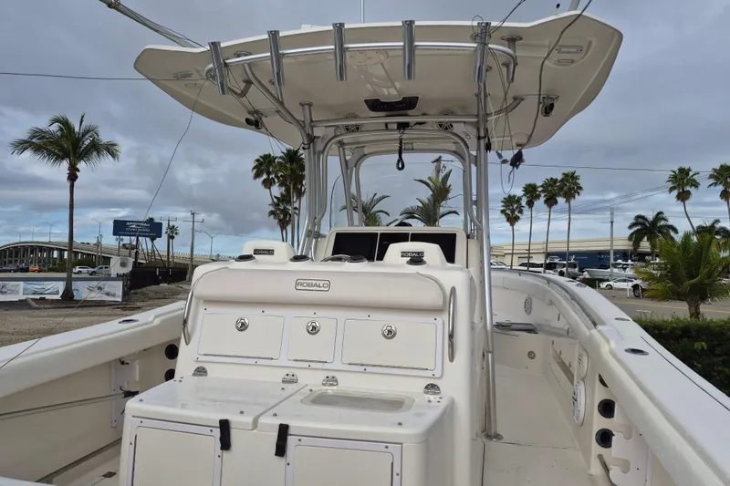 Slide: The Image of 2014 Robalo R300 Center Console boat with T-top, docked near palm trees. - 15