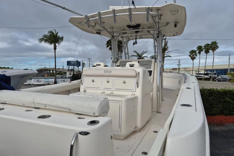 Slide: The Image of 2014 Robalo R300 Center Console boat with T-top and seating, docked near palm trees. - 18