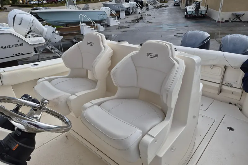 Slide: The Image of 2014 Robalo R300 Center Console boat with dual white seats and steering wheel. - 9