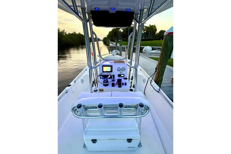Slide: The Image of 2020 Bulls Bay 2400 boat interior with steering console and seating, docked by a serene waterway. - 27