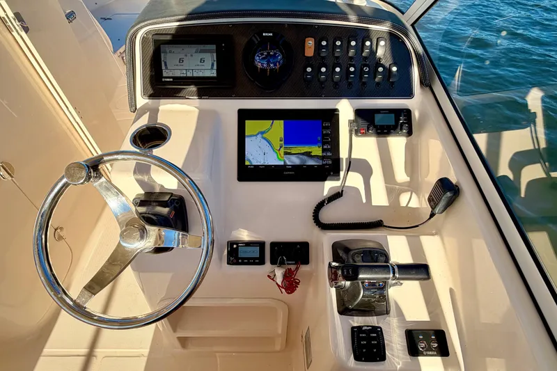 Slide: The Image of 2019 Grady-White Freedom 285 boat dashboard with steering wheel and navigation controls. - 20