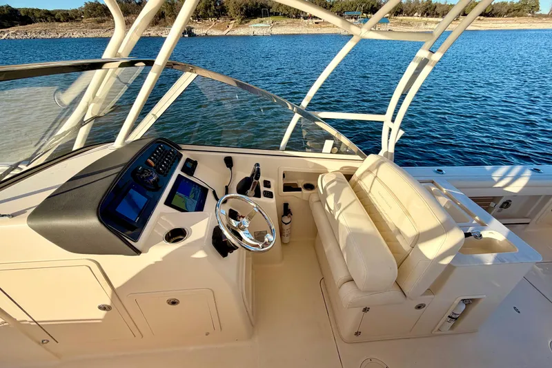 Slide: The Image of 2019 Grady-White Freedom 285 boat interior with helm and seating, on a serene lake. - 23