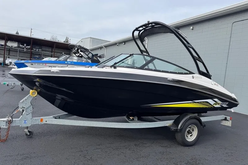The Image of 2017 Yamaha AR195 boat on trailer, black and white design, parked outdoors. - 0