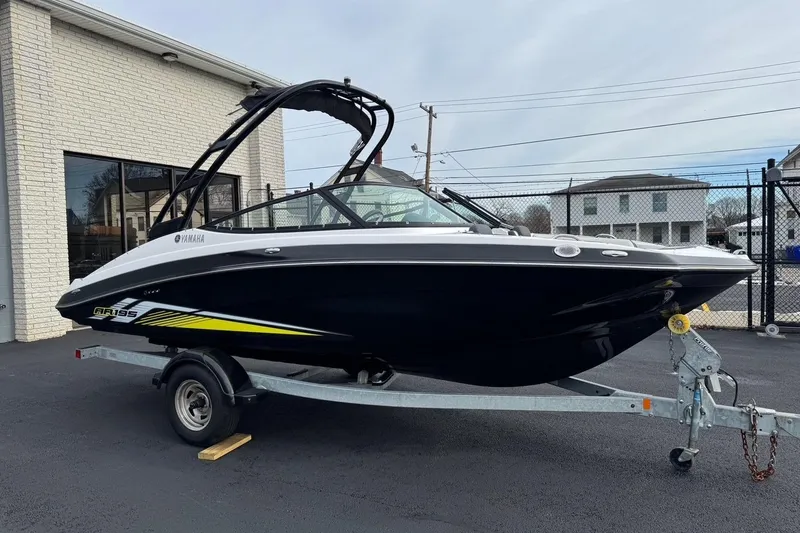 Slide: The Image of 2017 Yamaha AR195 boat on trailer, black and white design, parked outside a building. - 1
