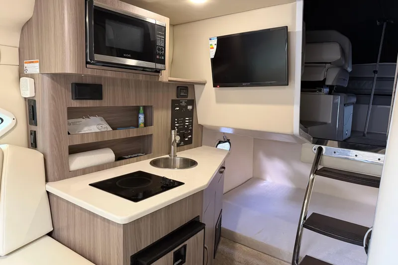 Slide: The Image of 2021 Regal 26 XO boat interior with kitchenette, microwave, TV, and ladder to cabin. - 19