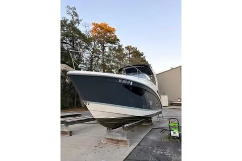 Slide: The Image of 2021 Regal 26 XO boat on dry dock, surrounded by trees and a building. - 26