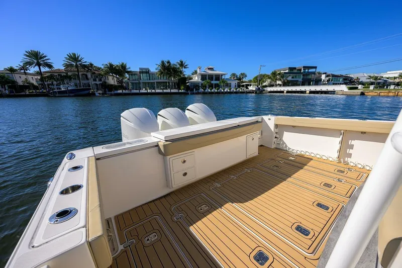 Slide: The Image of 2018 Pursuit S 408 Sport boat with spacious deck, docked by waterfront homes. - 22