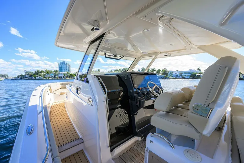 Slide: The Image of 2018 Pursuit S 408 Sport boat interior with helm, luxurious seating, and waterfront view. - 3