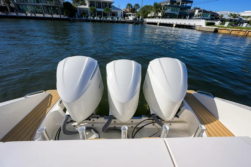 Slide: The Image of 2018 Pursuit S 408 Sport boat with triple outboard engines on a calm waterfront. - 43