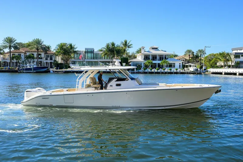 Slide: The Image of 2018 Pursuit S 408 Sport boat cruising on a sunny waterfront with luxury homes. - 45
