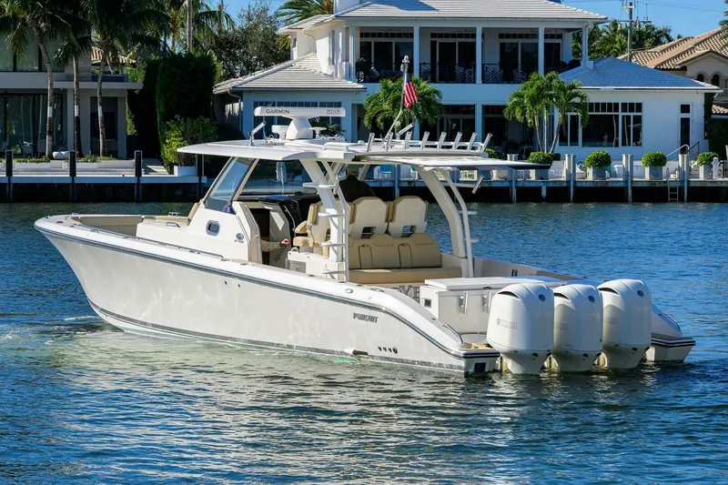 Slide: The Image of 2018 Pursuit S 408 Sport boat cruising on a sunny waterfront near luxury homes. - 50