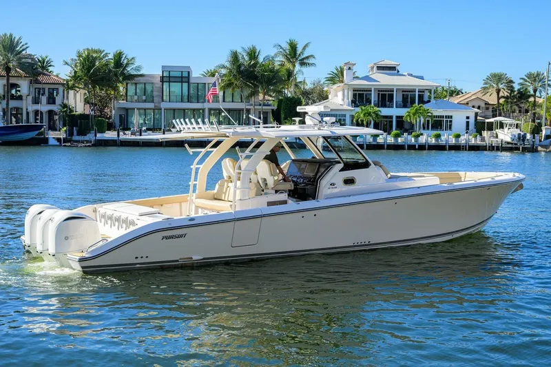 Slide: The Image of 2018 Pursuit S 408 Sport boat cruising on a sunny waterfront with luxury homes. - 6