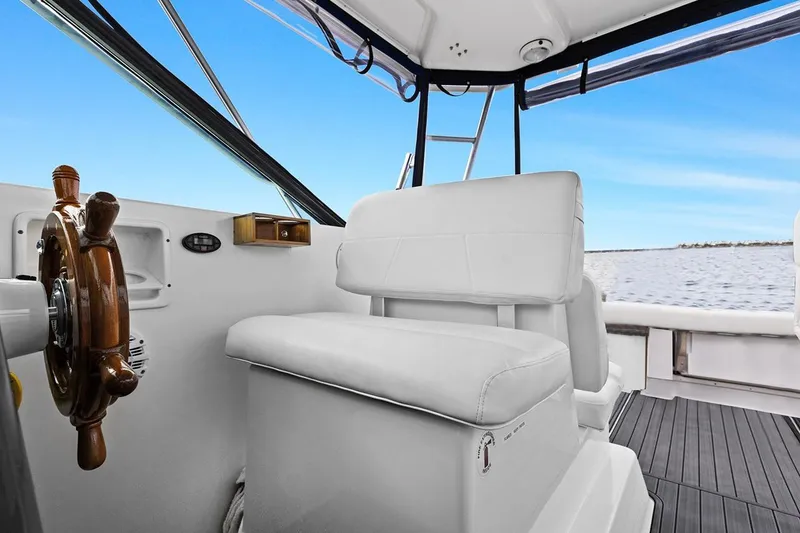 Slide: The Image of 2005 Tiara Open Classic boat interior with white seating and wooden steering wheel. - 8
