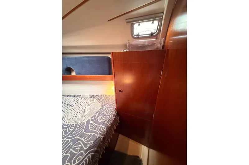 Slide: The Image of Interior cabin of 1997 Beneteau Oceanis 351 sailboat with wooden cabinetry and patterned bedding. - 57
