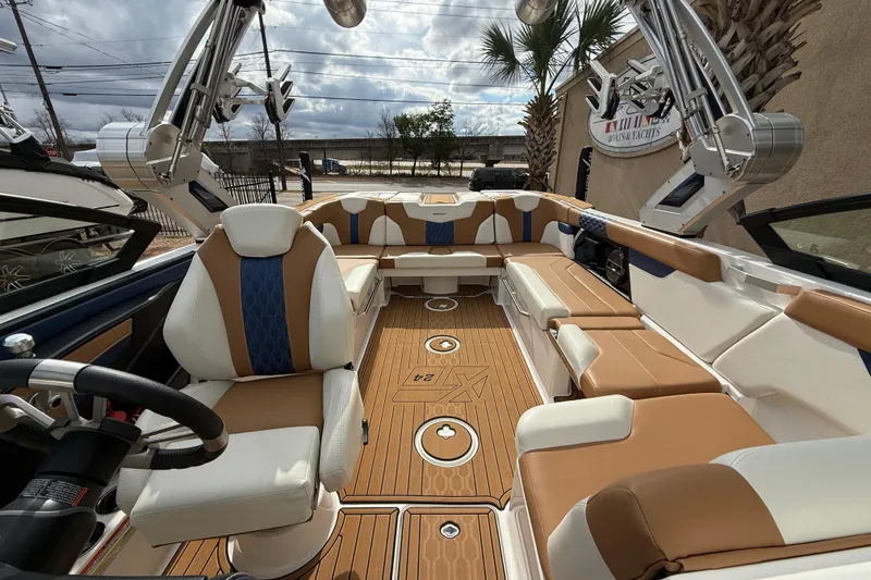 Slide: The Image of Luxurious 2022 MasterCraft XT24 boat interior with tan and white seating, under a cloudy sky. - 14