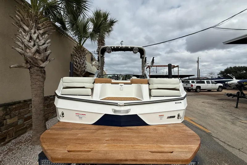 Slide: The Image of 2022 MasterCraft XT24 boat with cushioned seating, parked outdoors under cloudy skies. - 6