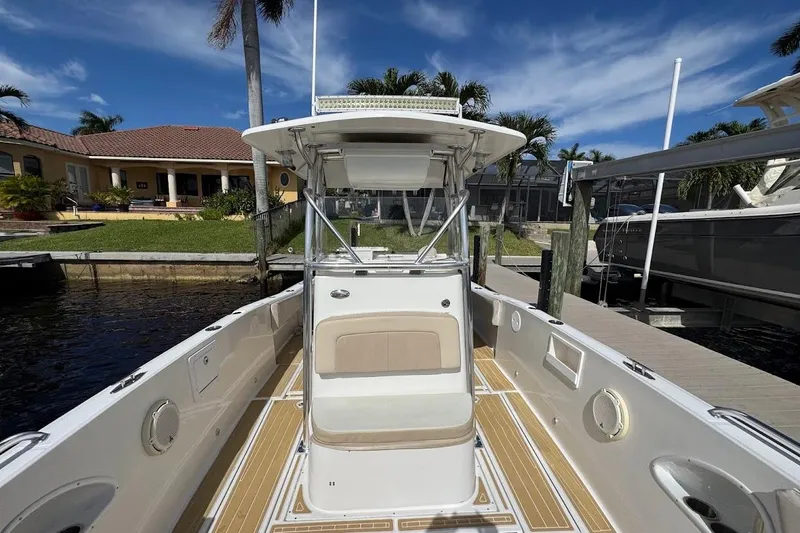 Slide: The Image of 2014 Stamas 317 Tarpon boat interior with seating and storage, docked by calm water. - 14