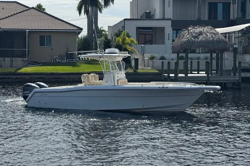 Slide: The Image of 2014 Stamas 317 Tarpon boat on a calm waterfront, with modern houses in the background. - 8