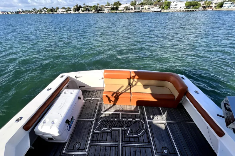 Slide: The Image of 1996 Wellcraft 330 Coastal boat deck with Igloo cooler and cushioned seating under blue sky. - 24